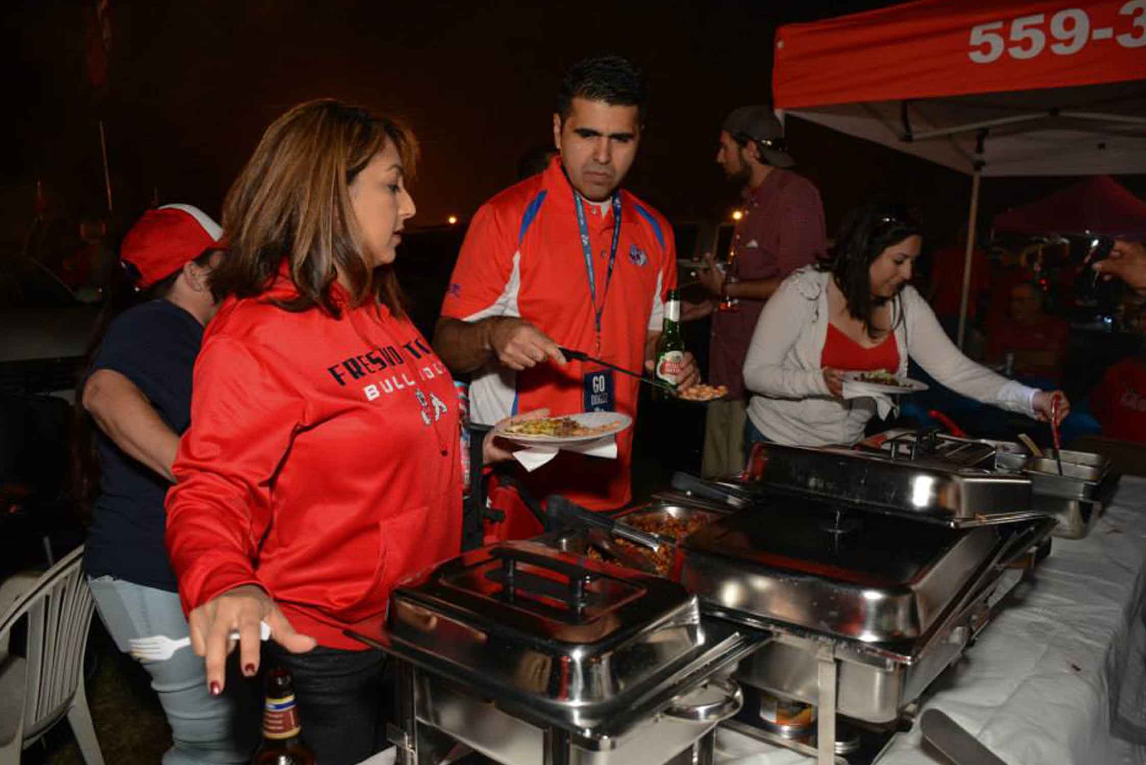 Members serving food to attendees at an event held by La Raza.
